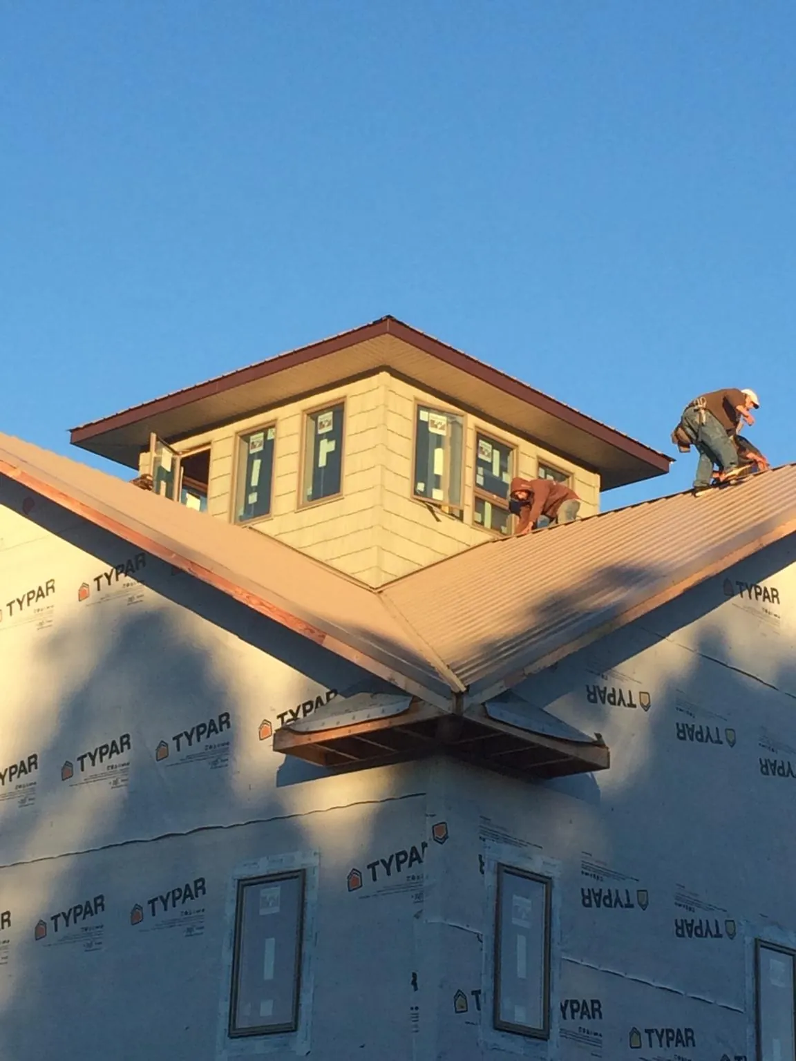 Roofers working around a rooftop cupola on a new metal roof at sunset — Roof Waterproofing in Williams by Roofing Brothers